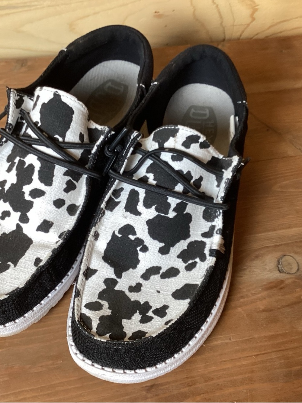 Hey Dude Women Cow Print Slip-On Sneakers in Black & White